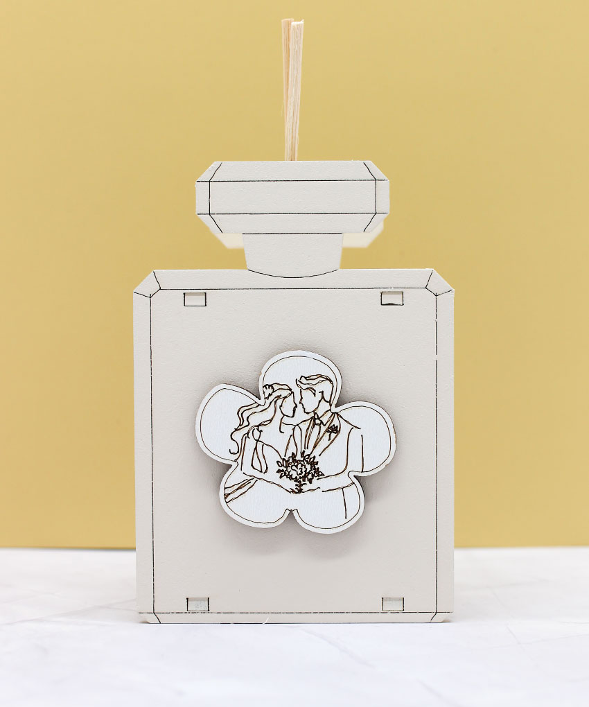 CR6076 – Bomboniera Profumatore a Forma di Bottiglia con Simbolo Coppia Sposi colore Sabbia – 7 × 11 cm